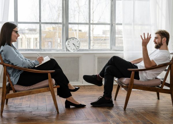 A therapist engaging in a counseling session with a male patient to support mental health.
